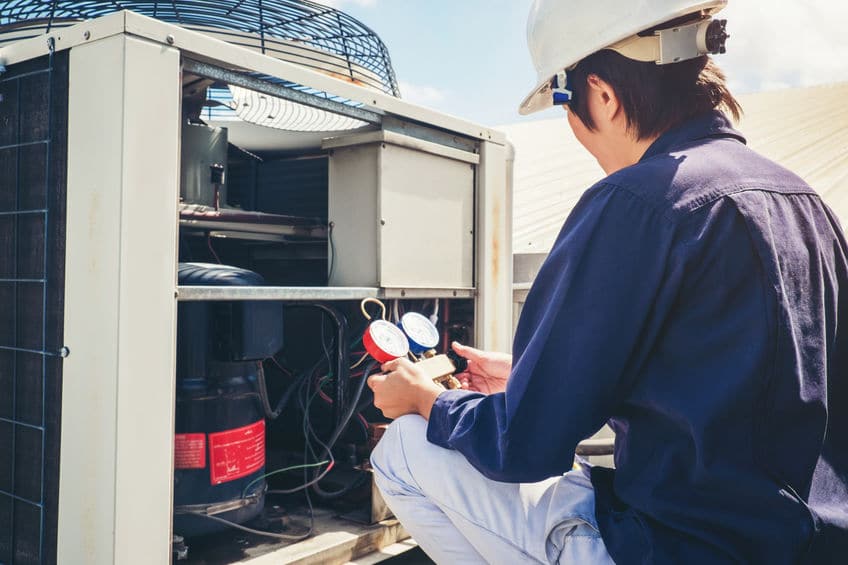 Technician checking HVAC system with gauge tools.