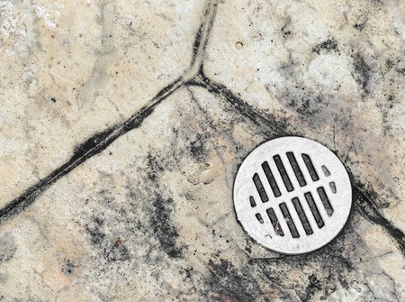 Floor drain on cracked concrete surface.