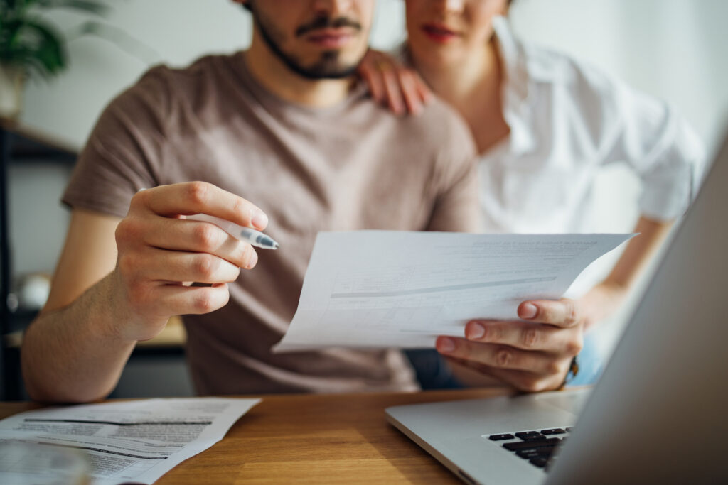 Two people at a laptop, looking at bills.